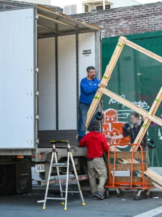 A big window is being transported by a moving services crew.