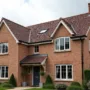 Charming British home with diverse roof tiles—clay, slate, concrete, synthetic—under a cloudy UK sky, showcasing durable and stylish roofing options.