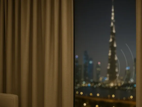 Thick soundproof curtains drawn across a large window in a modern Dubai apartment at night, softening city noise with a blurred Burj Khalifa skyline outside.