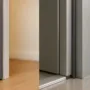 Side-by-side close-ups: residential door with foam weatherstripping and sweep (left) vs. commercial door with silicone bulb gasket and automatic door bottom (right).