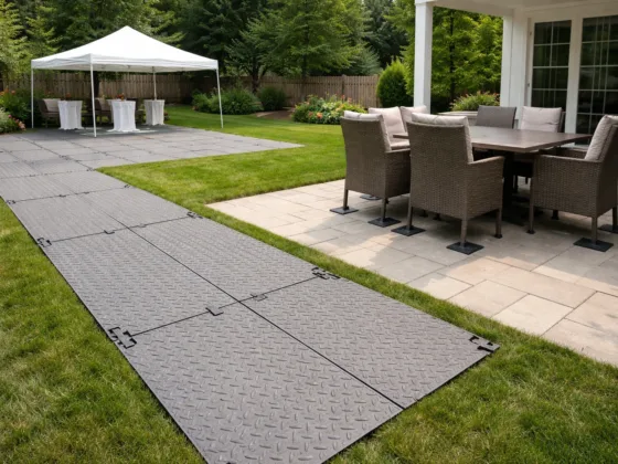 Temporary ground protection panels installed over lawn beside a residential patio to prevent surface damage during an outdoor event